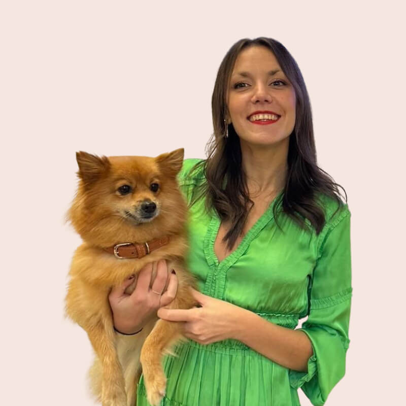 Une femme vêtue d'une robe verte tenant un petit chien.